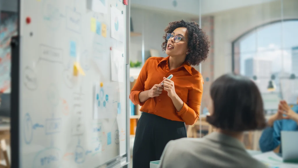 eine Frau steht mit einem Stift an einem Whiteboard