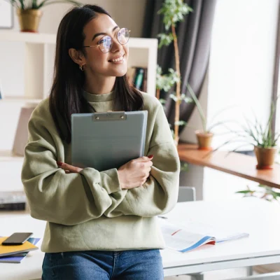 Bürokauffrau steht mit einem Klemmbrett im Büro